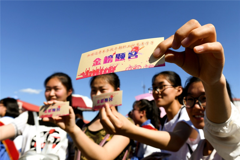 6月5日，大杨树镇即将参加高考的部分学生手拿印有“金榜题名”的书签准备登车。
