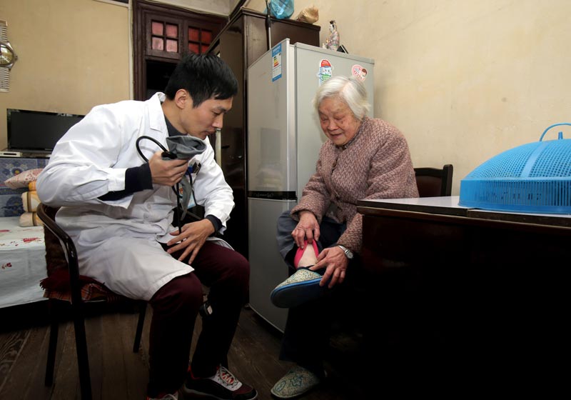 上海黄浦区瑞金二路街道社区卫生服务中心的家庭医生魏魏在社区居民李阿婆的家中查看她脚部浮肿的情况（2月10日摄）。截至今年第一季度，家庭医生签约服务已走进上海218家社区卫生服务中心。
