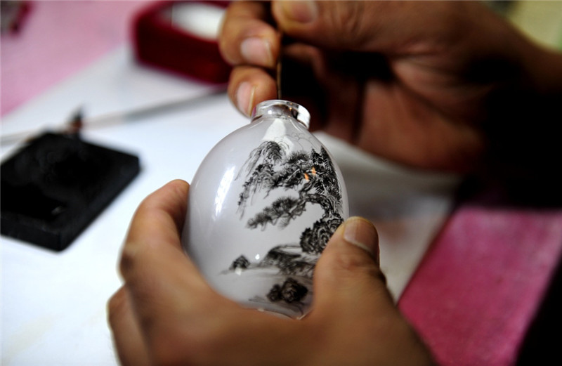 8月23日，天津市工艺美术大师王新年在展示鼻烟壶画技艺。