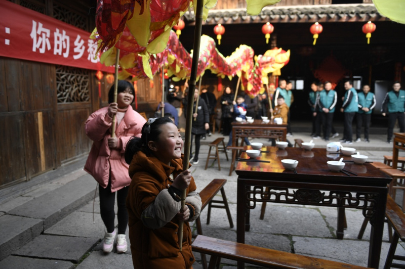 2月8日,小朋友在宁波市奉化区滕头村百年老屋院子里体验舞龙,等待"小