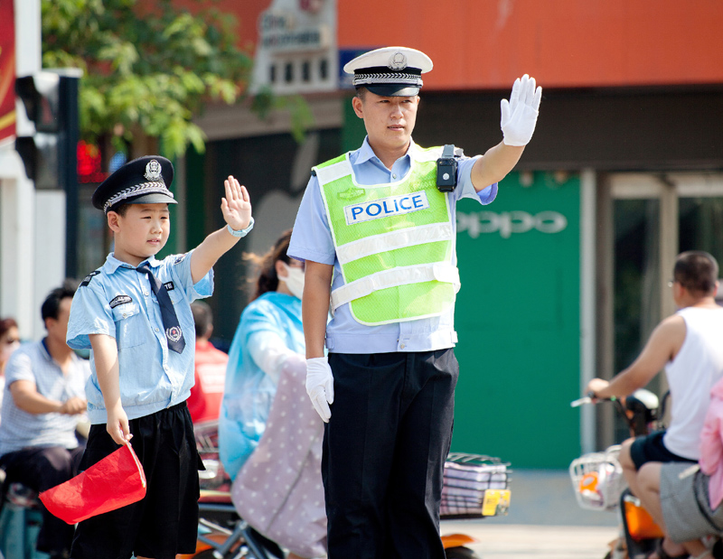 7月21日,"小交警"在民警的指导下体验指挥交通.