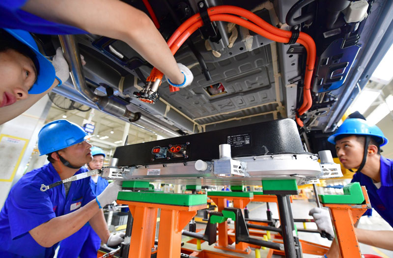 6月12日,工人在比亚迪西安基地总装车间为一辆新能源汽车安装电池包.