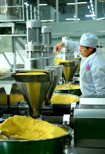的生产车间,工人将黄豆加入机械生产合渣粉