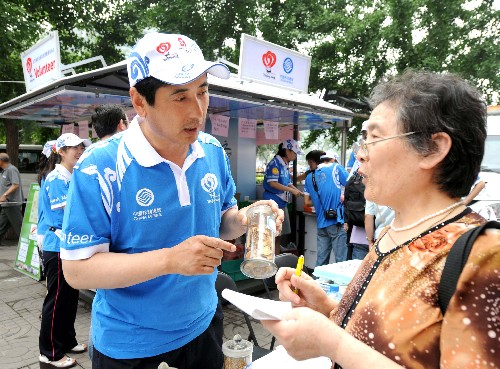 7月1日,一名城市志愿者(左)在北京图书大厦站点给一位市民介绍家庭常用中药的性能与使用方法。当日,首批200个北京奥运会城市志愿者服务站点投入使用,北京奥运会、残奥会城市志愿者正式上岗开展服务。据悉,在7月1日至10月8日的100天里,将有40万名城市志愿者,在北京市内的所有奥运会城市志愿者服务站点陆续上岗,为奥林匹克大家庭成员、国内外媒体记者、观众、游客以及首都广大市民提供信息咨询、应急、语言翻译等服务。 新华社记者罗晓光摄