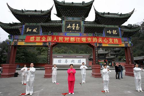 1月23日,在玉垒山广场牌坊前排练的都江堰市某艺术团成员打出拱手拜年的手势。新华社记者 郑悦 摄