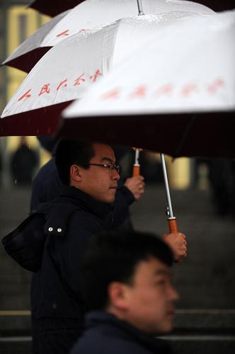 3月14日,第十一届全国人民代表大会第三次会议将在北京人民大会堂举行闭幕会。北京下起了雨夹雪,工作人员打着伞迎接代表。新华社记者 金良快 摄