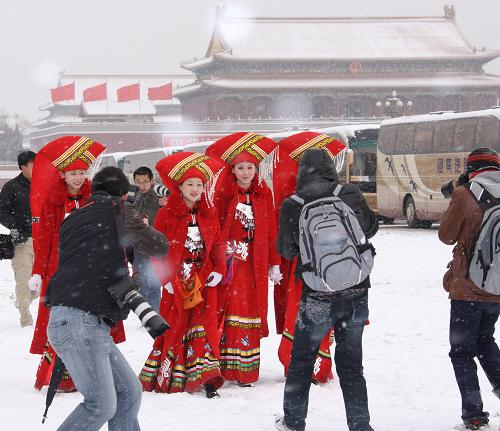 3月8日是国际劳动妇女节,一场春雪降临京城,身着红色民族服装服务两会的广西大厦服务人员来到天安门广场,在白雪的映衬下分外靓丽,成为记者拍摄的焦点。 新华社记者 陈建力 摄