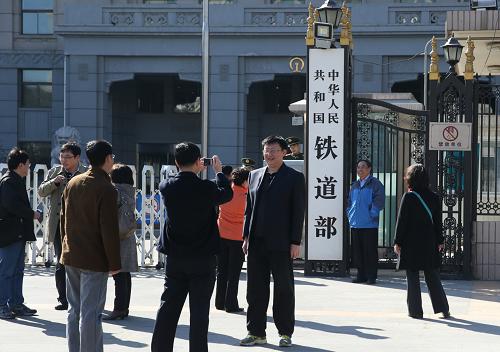 3月10日,人们在铁道部前留影。 根据3月10日提请全国人大会议审议的国务院机构改革和职能转变方案,将不再保留铁道部,实行铁路政企分开。将铁道部拟订铁路发展规划和政策的行政职责划入交通运输部;组建国家铁路局,由交通运输部管理,承担铁道部的其他行政职责;组建中国铁路总公司,承担铁道部的企业职责。 新华社记者 王申 摄