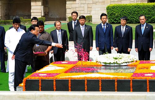 李克强向甘地墓敬献花圈 5月20日,中国国务院总理李克强在新德里向甘地墓敬献花圈。这是在敬献花圈后,李克强向甘地墓抛撒花瓣。 新华社记者 李涛 摄