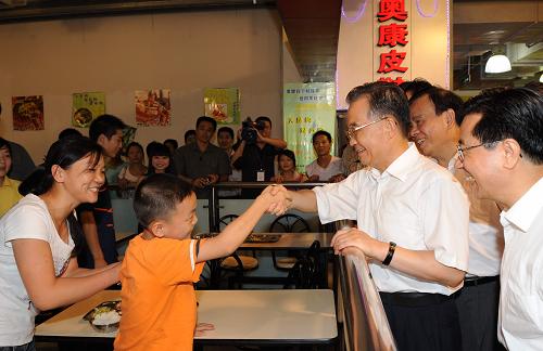 8月23日,温家宝在商场里的快餐厅与正在和妈妈一起吃饭的尹锐小朋友打招呼。当日下午6时许,正在浙江考察的中共中央政治局常委、国务院总理温家宝来到温州市上江路的易初莲花购物中心,看望在这里购物的群众。温总理亲切询问正在商场快餐厅吃饭的尹锐小朋友,他是哪里人,吃的快餐是多少钱。尹锐的妈妈尹翠还回答说,他们是湖北黄石市阳新县三溪镇黄冲村人,那份她和儿子一起吃的快餐是5元钱。温总理又问她的工作情况,家里有什么困难。尹翠还说,她来温州打工已经6年了,丈夫因患白血病今年7月份去世了,家里现在很困难。儿子尹锐开学就要上小学5年级了,本来在火车站附近上学,现在想转到自己工作的工厂附近,找一所学校就近上学,方便照顾。但是问了厂附近的3所学校,都不同意。眼看到了秋季开学的时候,她正在发愁,没想到今天碰到了温总理,真是太高兴了。尹翠还边说边哭了出来。询问完情况,温总理仔细叮嘱在现场的温州市领导去调查一下,看看能不能帮助解决一下尹锐的转学问题。24日早上,记者得知,尹锐的转学问题已经得到妥善解决。 新华社记者 李学仁 摄