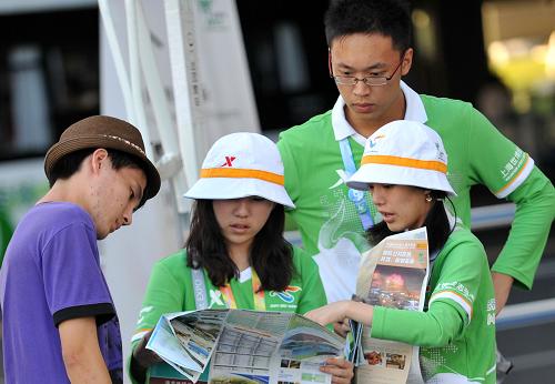 8月9日,在上海世博园内,几位志愿者在为一位游客指路.