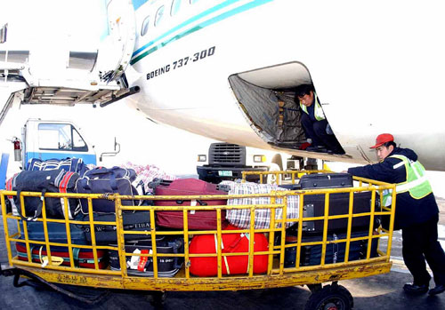   工作人员在北京首都国际机场为抵达航班的旅客装卸托运行李