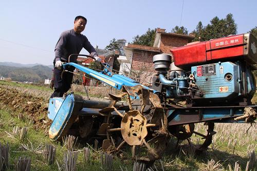 2月21日,江西省赣县白鹭乡龙溪村农民驾驶翻耕机在田间作业.