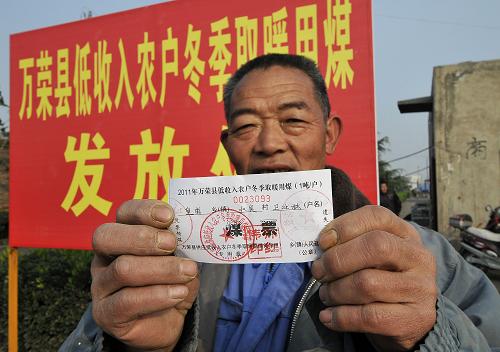 11月10日，在山西运城万荣县皇甫乡北吴村，农民展示自己刚领到的“煤票”。近日，万荣县的9万低收入农户每户凭“煤票”可免费领到１吨煤炭用以冬季取暖，受益人口达35.89万人。山西省政府不久前下发《关于供应低收入农户冬季取暖用煤的管理办法》，要求为全省低收入农户发放每户１吨煤的“煤补”。 这项政策从今年开始执行，直到2015年底。这意味着未来5年内，山西省数百万户农民每年冬天都能免费获得１吨煤炭。新华社发（闫鑫 摄）