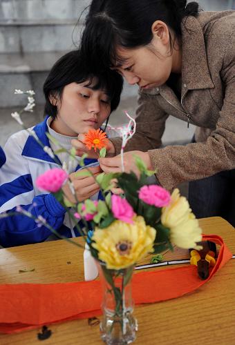 5月16日,长沙县特殊教育学校的一位老师在指导学生制作纸花。 当日,湖南省长沙市特殊教育成果展在湘江畔风帆广场举行。来自长沙地区几所特殊教育学校的学生通过各种才艺表演,展示他们的自信和美丽。 新华社记者李尕摄