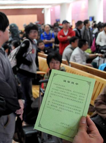 7月26日,一名旅客在候车室阅读火车站提供的晚点列车信息提示卡。 新华社记者 文涛 摄