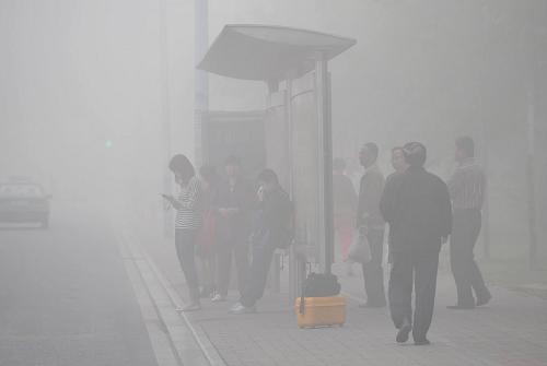 10月9日清晨,合肥街头大雾笼罩,一些乘客在大雾弥漫的公交站台候车。
