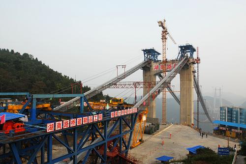 图为建设中的矮寨特大悬索桥(10月20日摄)。 10月20日,建设中的矮寨特大悬索桥的主缆完成了最后一根索股的架设,标志着大桥的索塔、主缆、钢桁梁三大主体工程完成了两项。 矮寨特大悬索桥是国家高速公路重点规划的8条西部通道之一的长沙至重庆通道,湖南段的吉(首)茶(峒)高速公路中的重点工程,在吉首市矮寨镇上空330米处横跨德夯大峡谷。桥身全长约1073.65米,其中悬索桥的主跨1176米。工程概算9.2亿元,预计2011年年底建成通车。 新华社记者范军威摄