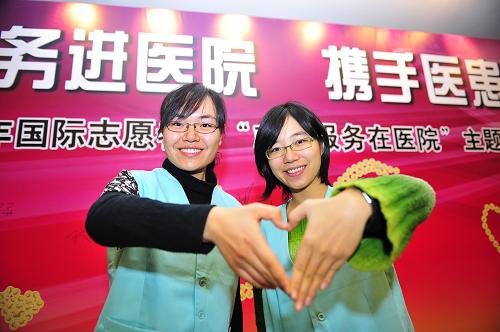 12月4日,来自北京大学医学部的志愿者贾茹(右)和同学在启动仪式上打出“爱心”手势。 当日,由卫生部、中宣部、教育部、民政部、团中央、全国妇联、全国总工会、中央文明办等单位联合举办的“2009年国际志愿者日‘志愿服务在医院’主题活动”在北京大学人民医院举行启动仪式。据悉,北京大学人民医院志愿者团队自今年4月份开始工作以来,共开展志愿服务173天,为医院提出合理化建议99条,实施一系列方便医患的服务举措,树立了良好的社会形象。目前,北京大学人民医院共有注册志愿者416人,其中大多数是从事医疗职业者或在京医学院校的学生。12月5日是第24个国际志愿者日。 新华社记者 杨光 摄
