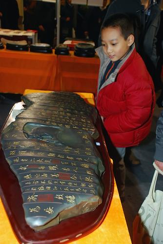 11月29日,在北京文博会上,一件刻有兰亭序的苜却砚吸引小朋友驻足观赏。新华社发(韩路 摄)