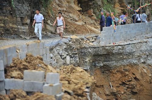 7月11日,人们步行通过被冲毁的遵义市正安县至道真县公路主干道。7月8日至11日,贵州省遵义市道真仡佬族苗族自治县遭遇强降雨袭击,最高降雨量达209毫米,强降雨持续时间达29小时。截至11日统计数据,全县受灾人口153900余人,失踪1人,伤32人。农作物受灾15165公顷,倒塌住房156间,损坏1189间。暴雨导致道路损毁严重,全县14个乡镇中有12个已不通路,4条出县公路仅有1条勉强通车。灾害已造成直接经济损失1.3亿元。目前当地党委政府已迅速采取措施抗洪救灾。新华社记者 刘续 摄