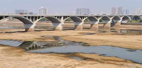 提前进入枯水期的长沙湘江橘子洲大桥段(10月6日摄)。由于连续晴热少雨,湘江长沙段10月6日水位跌破历史最低值。据长沙水文站提供的数据,截至当日上午8时,湘江长沙段水位回落至25.08米,比历史最低水位25.15米低0.07米。据悉,今年以来,湖南省平均降雨较常年偏少14%,尤其是8月份以来降雨严重偏少,导致江河水位持续走低。目前,湖南省防汛抗旱指挥部已采取相关措施,从上游调水、补水,并将在适当的时候采取人工降雨的方式,增加降雨量。同时,为确保城区安全正常供水,长沙已启动了湘江枯水期应急取水工程。新华社记者 龙弘涛 摄