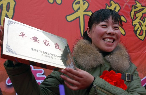 12月11日,安徽省亳州市举行“平安家庭”表彰会,一名女士展示颁发的“平安家庭”匾牌。当日,安徽省亳州市对全市范围内评选出的200户“平安家庭”进行公开表彰。这些家庭都有一个共同特点,就是通过“平安家庭”的创建,积极参与和谐社会建设,以家庭的平安促进社会的和谐。 新华社发(张延林 摄)