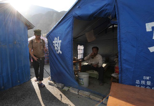 6月8日,在位于汶川县城岷江江边的救灾帐篷营地,一位受灾男子正在为帐篷营地喷洒消毒液。帐篷营地以帐篷为单位实行卫生防疫轮值。 汶川大地震发生已经近一个月。目前,汶川县城受灾群众情绪稳定,各项秩序正逐步恢复。 新华社记者申宏摄