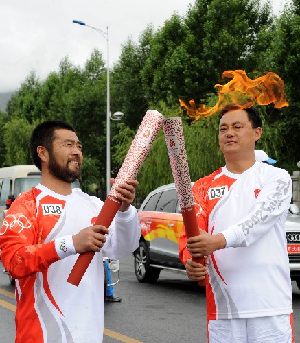 6月21日,火炬手张云宝(右)与下一棒火炬手才让扎西交接。当日,北京奥运会圣火传递活动在西藏拉萨举行。 新华社记者觉果摄