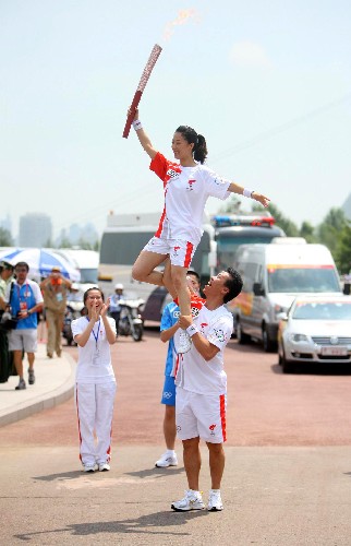 7月11日,火炬手申雪(上)与下一棒火炬手赵宏博交接。当日,北京奥运圣火在哈尔滨传递。 新华社记者邢广利摄