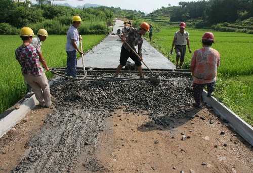 7月23日,筑路工人在紧张浇注通往休宁县万安镇福寺村的水泥路。这是该县最后几条正在建设中的通村公路之一。地处皖南山区的安徽休宁县2006年启动“村村通公路”工程,新建通村公路110多条,里程达347公里。到目前为止,全县90%的村已经通公路。 新华社发(倪受兵 摄)
