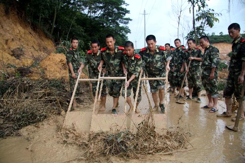 6月14日,深圳边防支队轮训队的官兵在宝安区章阁村路段清理塌方的淤泥。新华社记者 周文杰 摄