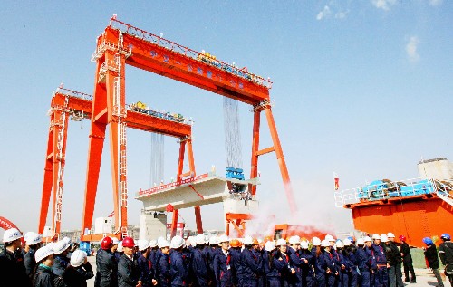 12月9日,在京沪高速铁路苏州制梁场,京沪高铁苏州段的首榀箱梁被两台大型提梁机稳稳提升至桥墩上。这标志着京沪高铁苏州至上海方向的箱梁提梁架设工程进入实质性阶段。京沪高铁全长1318公里,设计时速350公里,总投资超过2209亿元。项目建成后,北京至上海只需4个多小时。新华社发(王建中 摄)