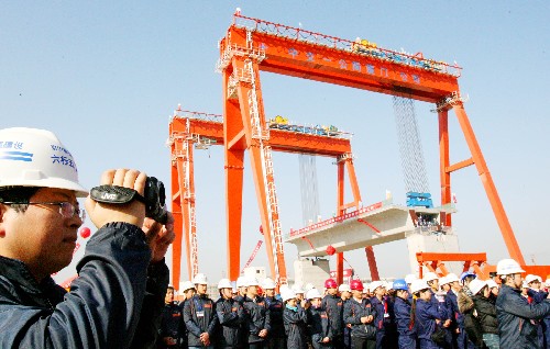 12月9日,京沪高铁指挥部一名工作人员在苏州制梁场拍摄首榀箱梁提梁上线情况。新华社发(王建中 摄)