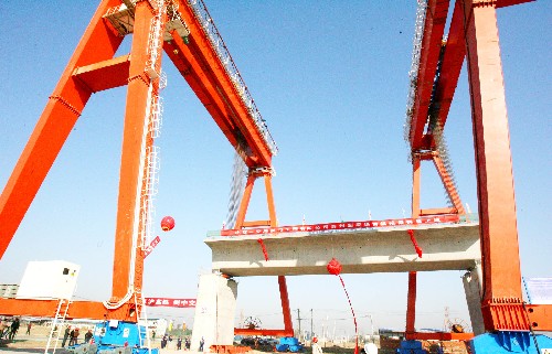 12月9日,在京沪高速铁路苏州制梁场,京沪高铁苏州段的首榀箱梁被两台大型提梁机稳稳提升至桥墩上。新华社发(王建中 摄)