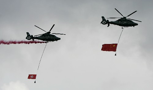 7月1日,2架分别悬挂着国旗和香港特区区旗的直升机在升旗仪式结束后从空中飞过。新华社记者 周磊 摄