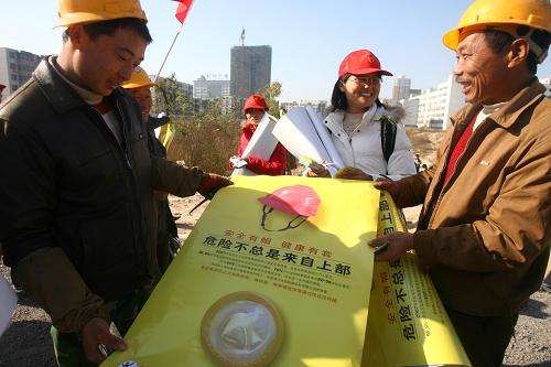 11月30日,河南农业大学的学生带着宣传海报、手册、安全套等物品来到郑州文化路某工地,向外来务工人员宣传艾滋病预防知识,迎接世界艾滋病日的到来。新华社发(陈晓东 摄)