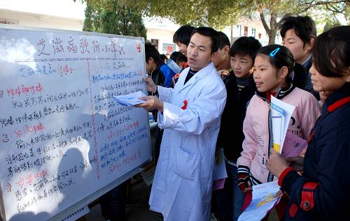 11月29日,在江西乐平市后港镇新乐中学校园,来自乐平市红十字会医院的医务人员向留守学生讲解艾滋病预防知识。连日来,乐平市红十字会医院抽调业务骨干人员,组成多个“防艾”宣传小分队深入到农村各中小学内,对留守学生进行艾滋病相关知识的教育,免费发放有关预防艾滋病的图书、手册等宣传资料,以提高学生们对艾滋病的科学认识。新华社发(朱定文 摄)