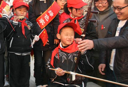 11月30日,一名大学生志愿者教一名艾滋病患儿拉二胡。当日,山西省临汾市红丝带小学的12名艾滋病患儿在老师带领下,走进山西师范大学校园,感受大学生的丰富生活,与大学生志愿者进行交流。新华社发(王辉耀 摄)