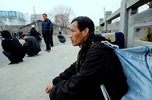 2月10日,一位来自河南的农民工在福州一路边用工市场等待招工。他抵达福州7天了,由于对当地情况不了解,每天都来火车站附近的这一路边用工市场寻找工作。新华社记者 张国俊 摄