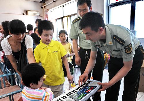 6月1日,秦皇岛边防支队干警向福利院的孩子赠送电子琴。当日,秦皇岛边防检查站和秦皇岛边防支队的官兵们带着生活、学习用品和玩具来到秦皇岛社会福利院看望孤残儿童,与孩子们共度“六一”儿童节。 新华社记者 杨世尧 摄