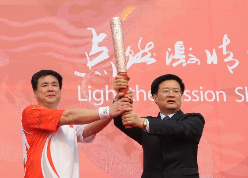 5月25日,江苏省委副书记王国生(右)在起跑仪式上将火炬交给第一棒火炬手孙志安。当日,北京奥运会圣火在江苏苏州传递。 新华社记者孙参摄