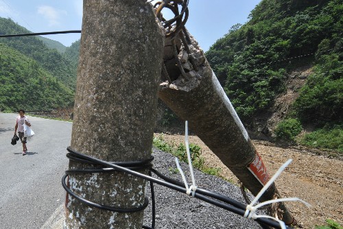 5月31日,一位村民从被洪水冲毁的电力、通讯设施旁走过。 受连日强降雨影响,贵州省的西部和南部遭受特大洪水与泥石流袭击,损失严重。目前,各级政府已调集2万余人的抢险队伍有序展开抢险救灾工作。 新华社记者杨俊江摄