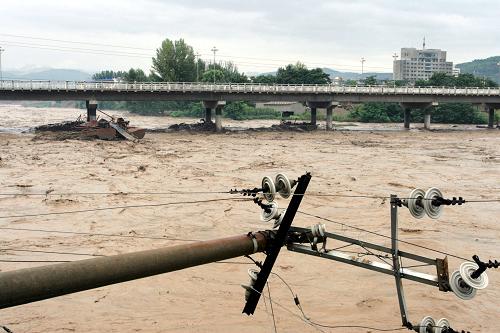 8月12日,城区路边的电线杆被洪水冲毁。 当日,甘肃成县普降大雨,其中北部山区黄渚发生特大暴雨。暴雨致使成县城区移动通讯中断,境内东河流域多艘采沙船被洪水冲至下游,致使东河两座大桥受到严重撞击,大桥桥体出现多处裂缝,目前东河两座大桥已被交管部门戒严,东河两岸交通中断。成县境内受灾最为严重的黄渚镇通讯、交通中断,无法与外界取得联系。 新华社发(燕海潮 摄)