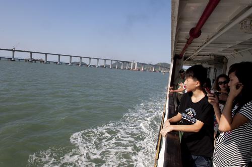 在由平潭驶往福清的轮渡上,乘客在观看海峡大桥雄姿(8月12日摄)。 全长4976米、总投资逾11亿元的跨海大桥——福建平潭海峡大桥自2007年11月开工建设以来,目前已完成施工总产值超过90%,进入最后合龙冲刺阶段,计划于2011年元旦前建成通车。平潭海峡大桥是福建第一大岛——平潭岛的首条出岛快捷通道,大桥的建成将结束该岛40万居民长期依靠轮渡往来的历史。 新华社记者姜克红摄
