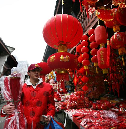 2月12日,一名刚从美国回国探亲的青年身着唐装,在浙江省舟山市西大街选购新春饰品。新华社发(胡社友 摄)