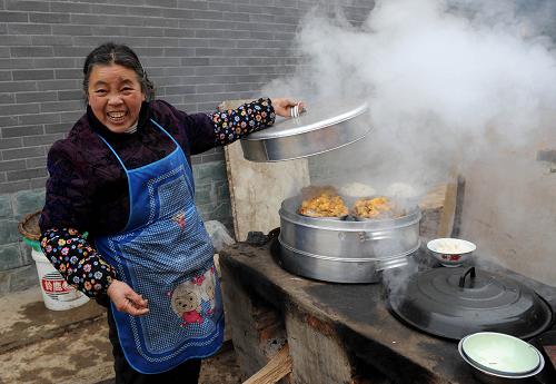 2月13日,在邛崃市南宝山永久安置点,一位来自青川的老人正在做团圆饭。新华社记者 陈燮 摄