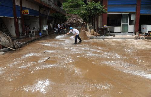 7月14日,达州市宣汉县华景镇,卫生防疫人员在对洪水冲过的路面消毒。新华社记者 江宏景 摄