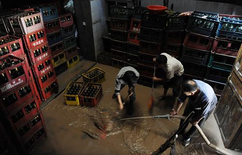 7月14日,达州市宣汉县华景镇,一商户正在清洗被洪水冲过的房屋。新华社记者 江宏景 摄