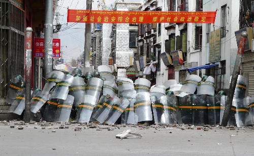 这张路透社播发的照片显示,3月14日,在拉萨市,处置打砸抢烧事件的武警用盾牌抵挡不法分子投掷的石块。新华社发